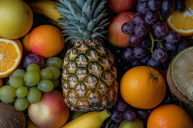 Vibrant assortment of fresh fruits including pineapple, bananas, citrus, grapes, and kiwis, beautifully arranged